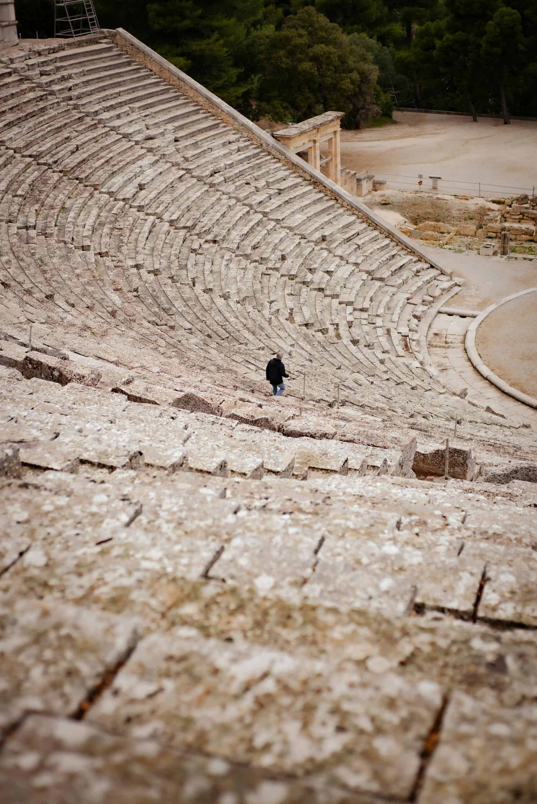 A person walking in the ancient Greek amphitheater in Nafplion, Greece, showcasing historic architecture.