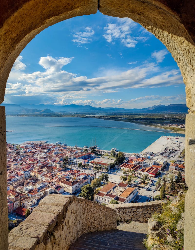 Captivating view of Nafplio town and coast through a historic stone archway.