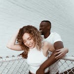 Happy couple smiling and embracing outdoors, showcasing joy and togetherness.