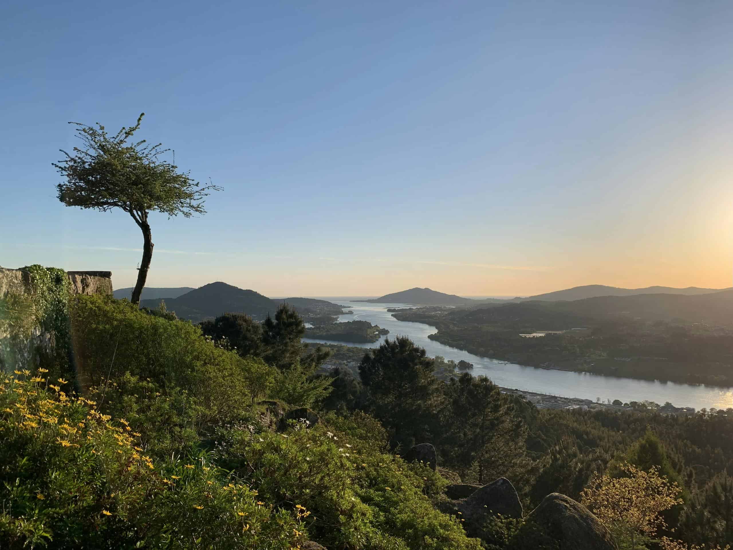 Idyllic sunset view over the Minho River with lush greenery and rolling hills.