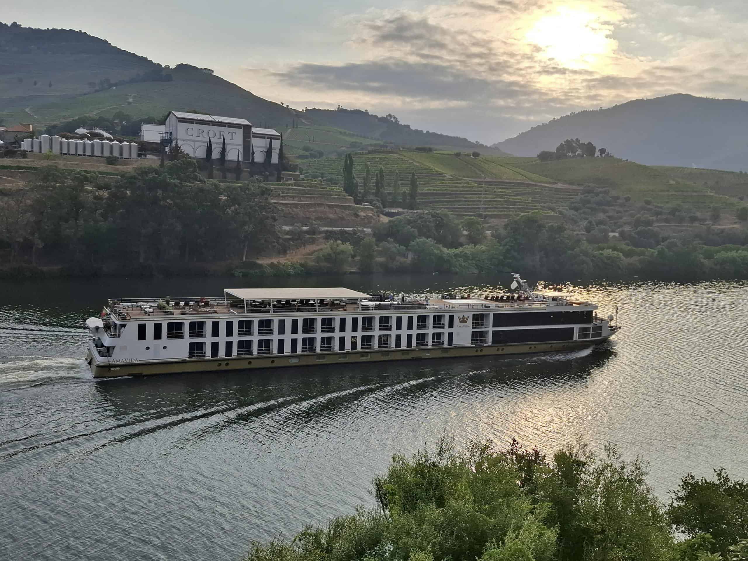 River cruise ship sailing on Douro River, Portugal at sunset.