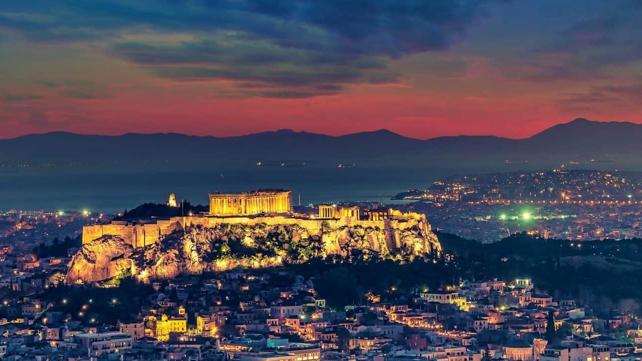 Stunning aerial shot of Athens cityscape with the illuminated Acropolis at twilight.