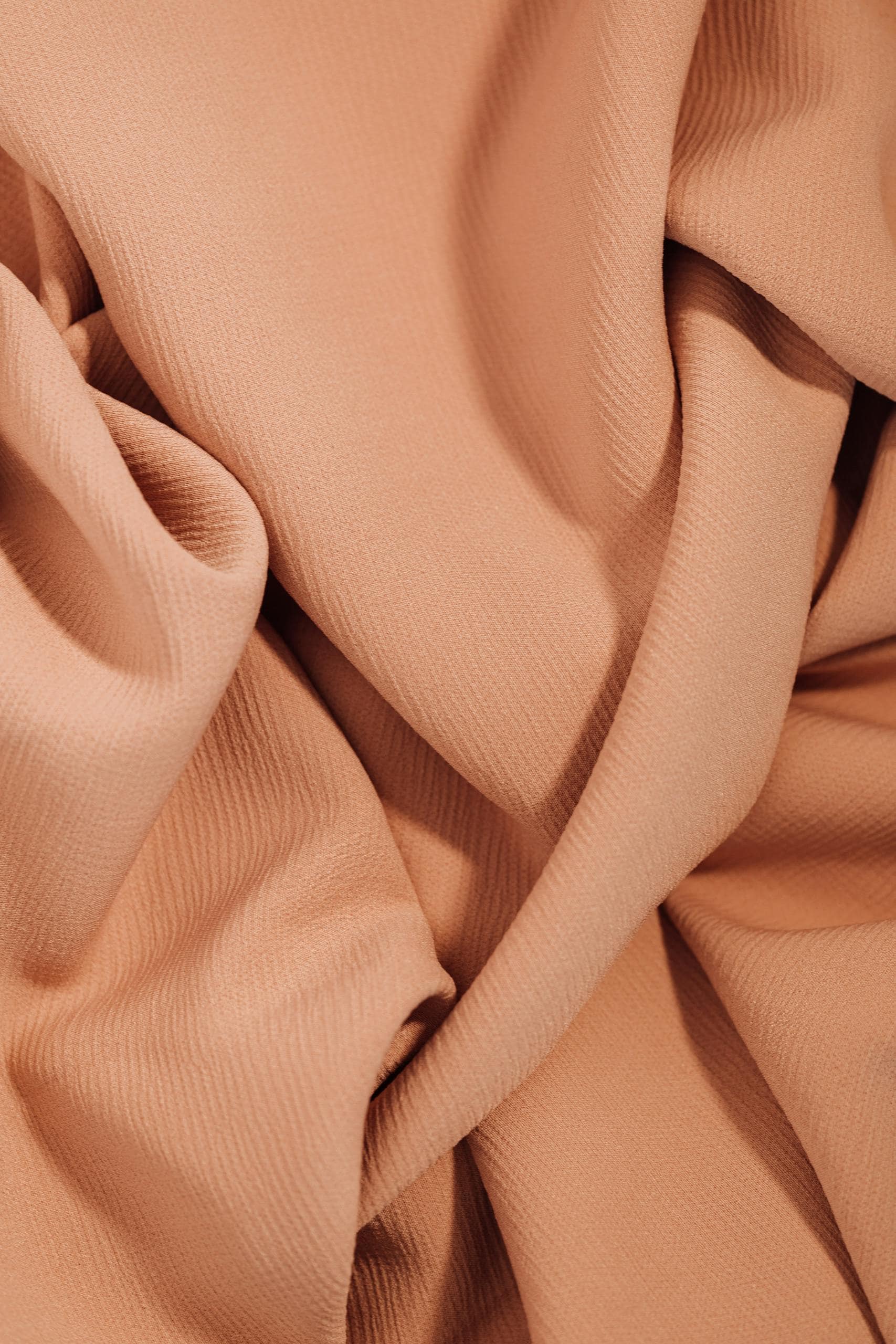 A detailed view of beige fabric emphasizing texture and ripples, suitable for backgrounds or textiles.