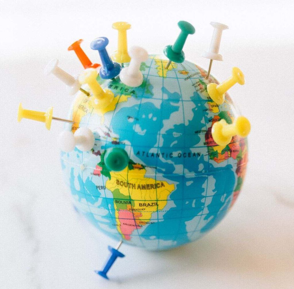 A small globe adorned with colorful pins, symbolizing travel and world exploration.